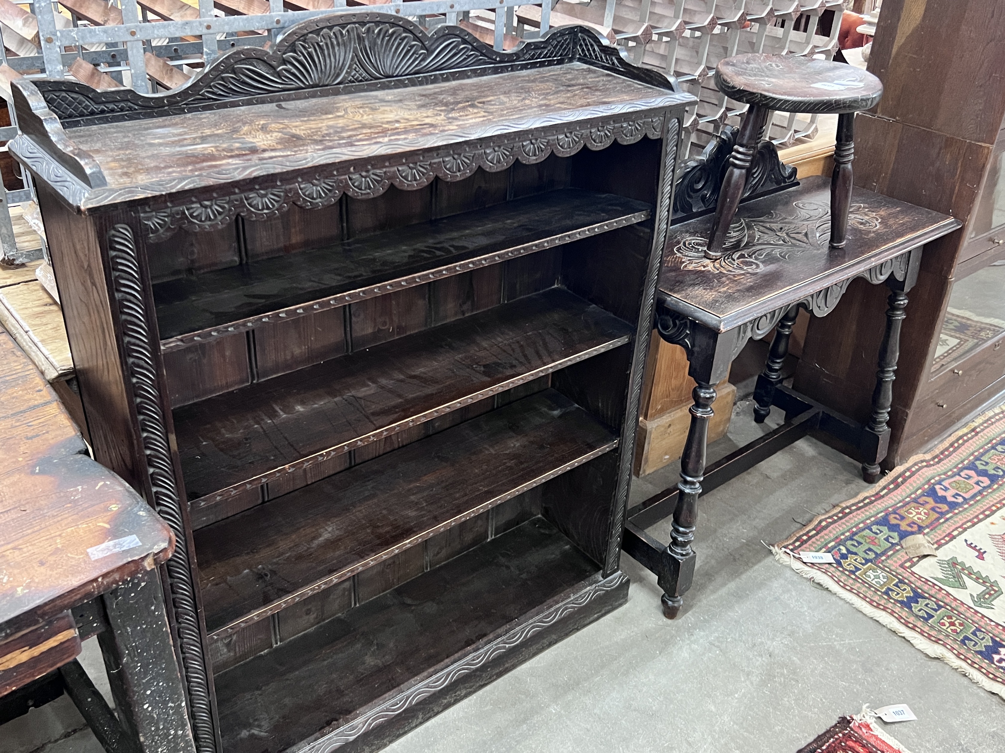 An early 20th century carved oak open bookcase, width 92cm, depth 26cm, height 114cm, together with a carved oak table and circular stool